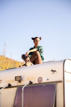 Young girl relaxing on the roof of a retro camper. Adventure in nature