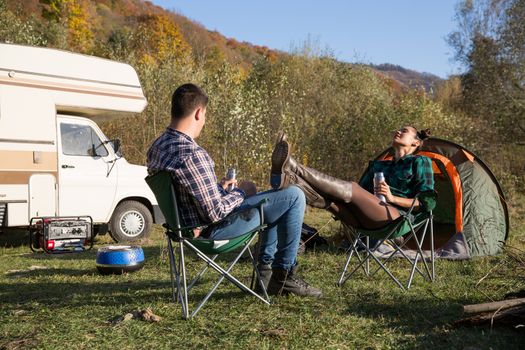 Woman relaxing and enjoying the wildernes of the mountains in autumn. Couple camping with retro camper van.