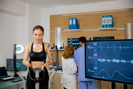 Female athlete who makes a physical effort on the stepper and has electrodes and heartbeats attached to it. Tests to run