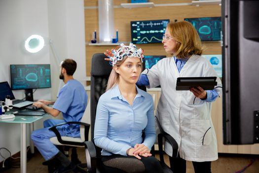 Doctor doing a girl's brain scan procedure in a scientific lab. Modern equipment