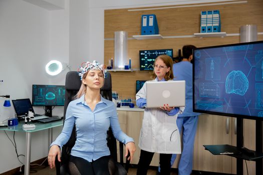 Doctor tracking live data on a laptop during a girl's brain scan procedure. Brain waves scanning headset