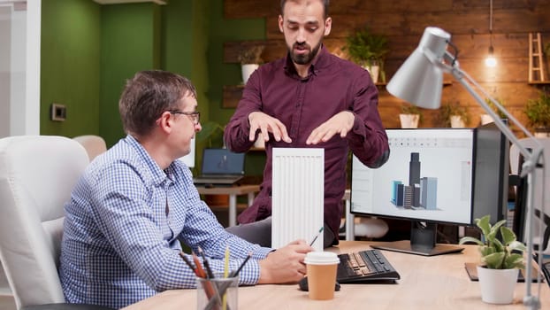 Two architects in cozy office talking about new buildings architecture, medium dolly shot
