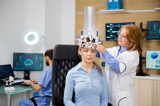 Doctor who puts brain waves scanning device on a female patient. Brain activity