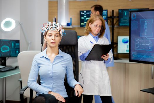 Doctor who notes in the clipboard the evolution of the patient during the neurology headset test. Brain test