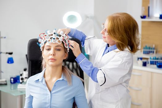 Doctor adjusting scanning device on the head of a female patient. Medical equipment