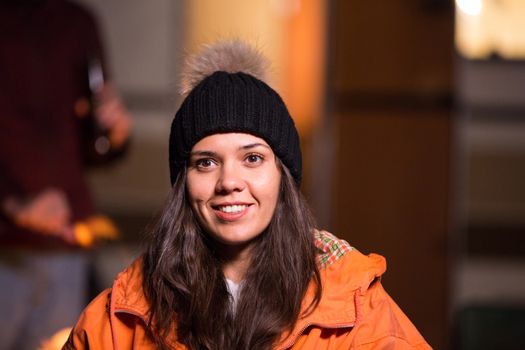 CLose up portrait of young woman smiling with retro camper van in the background. Camp fire.