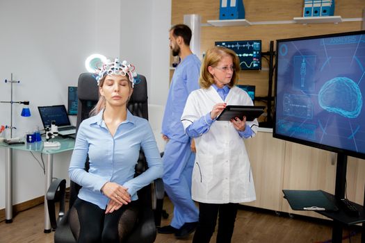 Doctor following the procedure of scanning a girl's brain. Neurology scanning headset