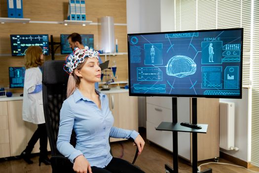 Patient woman who is brain scanned and his activity is shown on screen. Brain waves scanning helmet