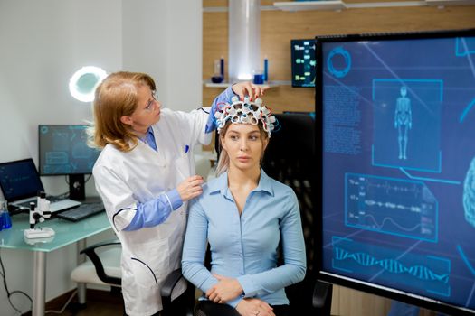Doctor adapting neurology helmet during a brain scan procedure. Modern lab