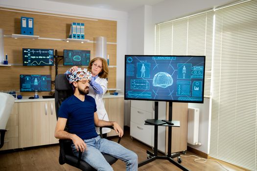 Doctor installing scanning device on the head of a male patient. Brain activity