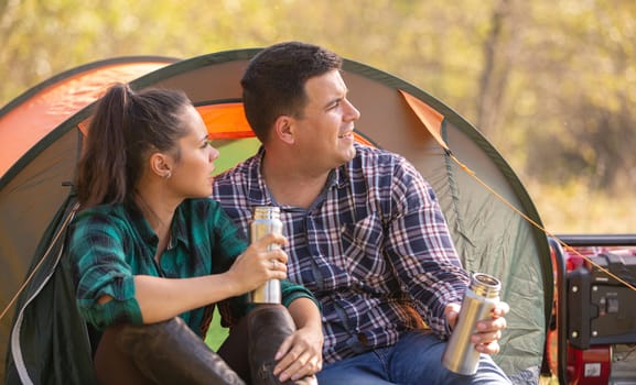 Loving couple enjoying a hot drink from the thermos and looking somewhere. Vacating nature