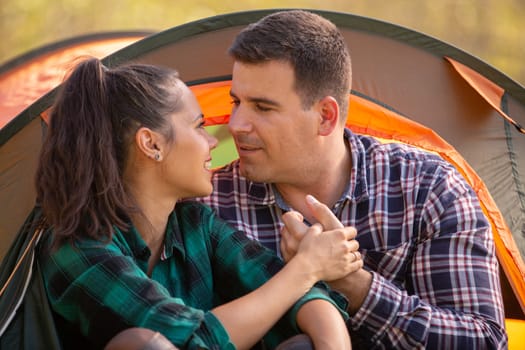 Loving couple looking at each other in front of the tent. People together