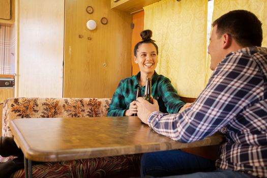 Woman looking at her lover and smiling stands at table in retro camper. Relax atmosphere