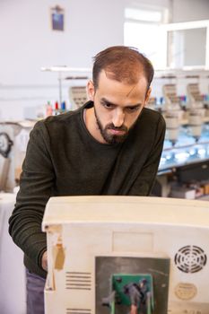 Young worker from the textile factory who controls an embroidery machine. Textile industry