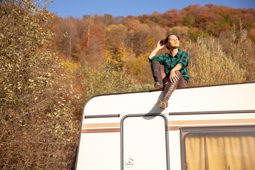 Young girl relaxing on the roof of a retro camper in a fall nightmare. Recreation vacation