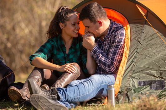 Boyfriend kissing his girlfriend's hand in front of the tent. Happy atmosphere