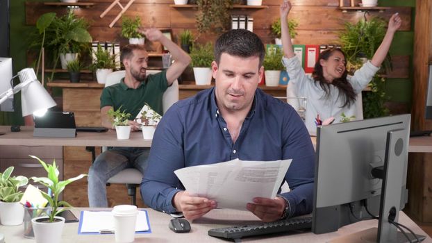 Office workers are celebrating a big sale. They throw papers in the air