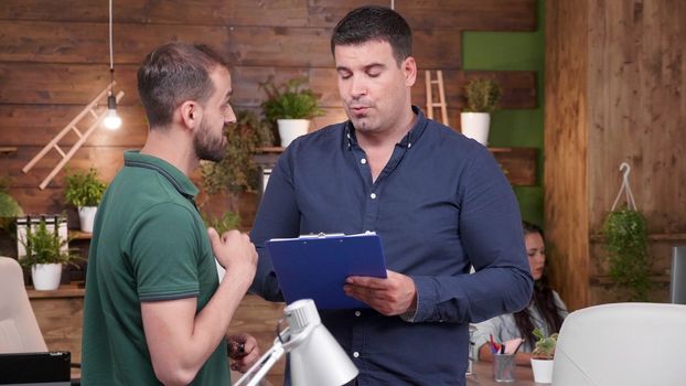 Zoom in portrait of male office working talking with another in cozy office environment. Slow motion footage