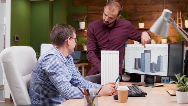 Two architects in cozy office talking about new buildings architecture, medium dolly shot