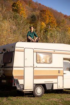 Caucasian girl meditating on the roof of a camper. In a sanny day autumn