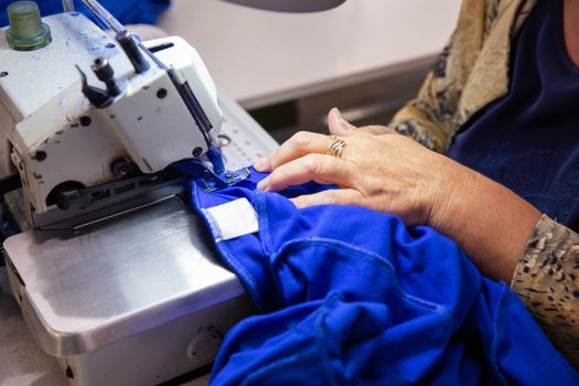 Close up with hands on a seamstress working on a sewing machine. Textile production