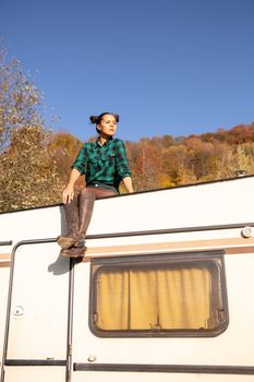 Young girl sitting on the roof of a retro camper admiring the view