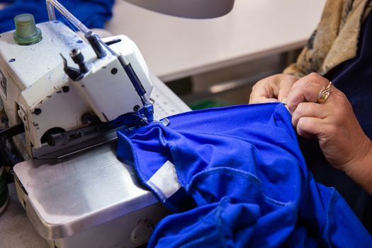 Close up with hands on a woman sewing something in the sewing machine. Textile industry