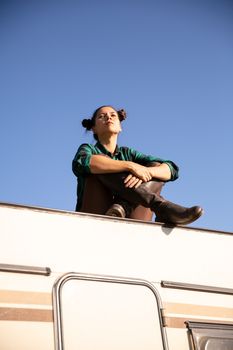 Young girl relaxing on the roof of a retro camper. Relaxing time