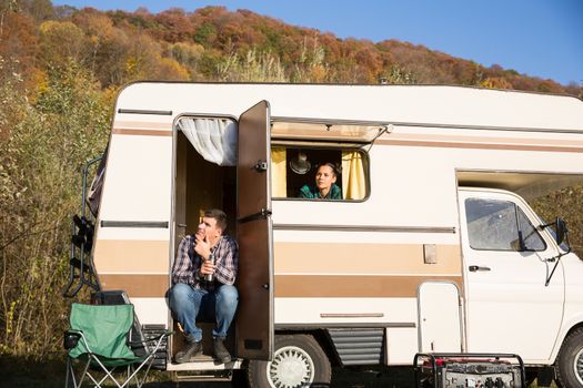 Couple admiring nature from inside of their retro camper van. Couple enjoying their vacation in the mountains.