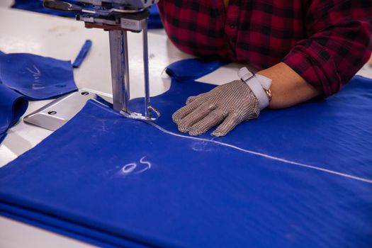 Close up with a woman using cloth cutting machine. Industrial machine