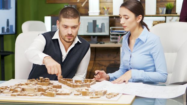 Team of architect working the urbanism of a modern town. Building models.