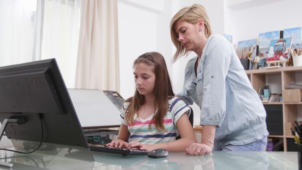 Responsible mother helping her daughter to finish the homework. Mom and her teenage girl solving a task together.