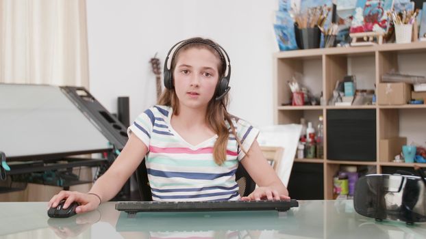 Young teenage girl playing a game on her computer. Young gamer playing an online game with her virtual friends.