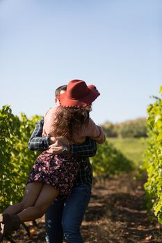 Cheerful young couple having a romantic moment in a vinyard. Woman with stylish hat in vinyard.