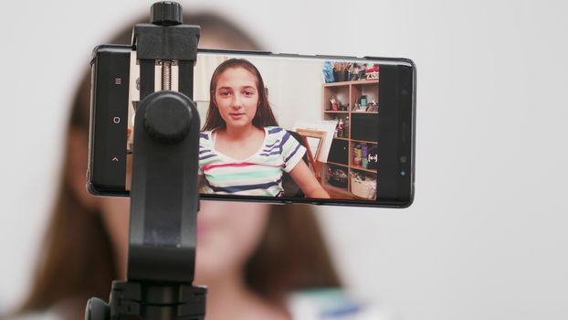 Teenage girl filming herself on a smartphone. Making a video for her channel to get more followers.