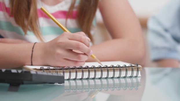 Girls hands with a pencil drawing in a notebook. Closeup of a teenage girls hand drawing on a paper.