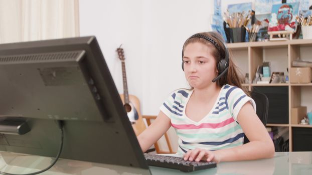 Teenage girl speaks with her virtual friend and texts using her keyboard. Young girl working on a desktop computer.