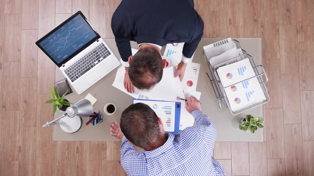 Top view of businessman in his office analysing different charts together with his business advisor.