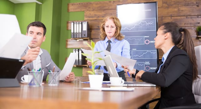 Female business executive delivering a presentation to her colleagues in conference room.