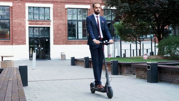 Businessman riding on an electric scooter in the business district. Getting out of the work