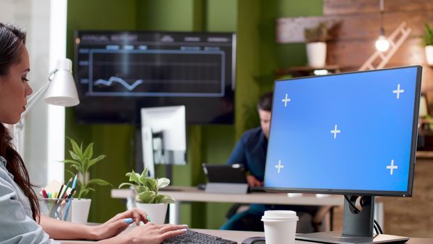 Woman working on a computer with a isolated mock-up in a busy office