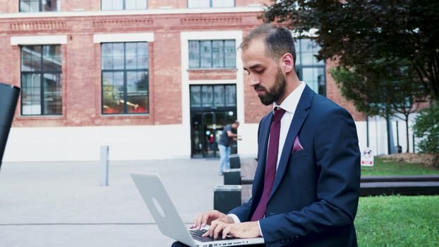 Young businessman working on the laptop in a business district, close up slow motion. Business on the go