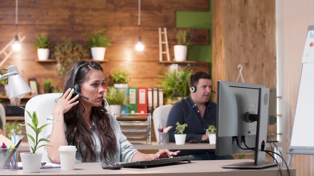 Customer service or sales operators working in a cozy office. Wide dolly shot