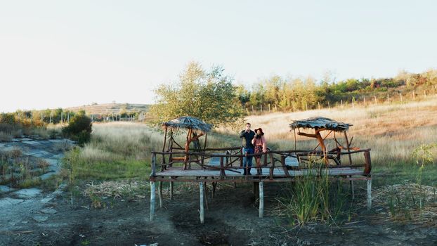 Couple enjoying a glass of wine on a pontoon in a rural are near a lake, aerial drone footage