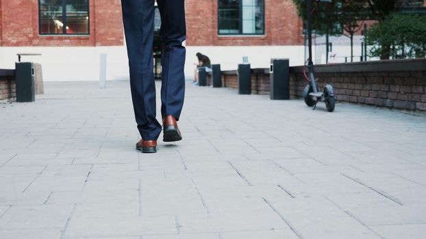 Unrecognisable businessman feet walking in the business district, back view tracking shot