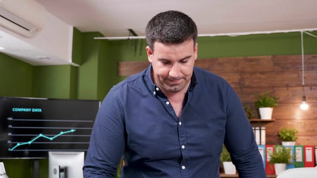Businessman comes to work with a cup of coffee in hands. He sits at his desk. Slow motion footage