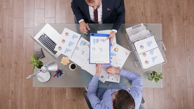 Top view of businessman in suit signing a contract after analysing agreement charts in a business meeting.
