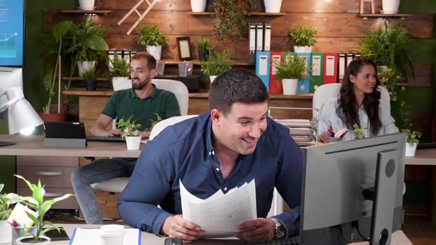 Office workers read an exciting email and are very happy. They all throw papers in the air. Slow motion footage
