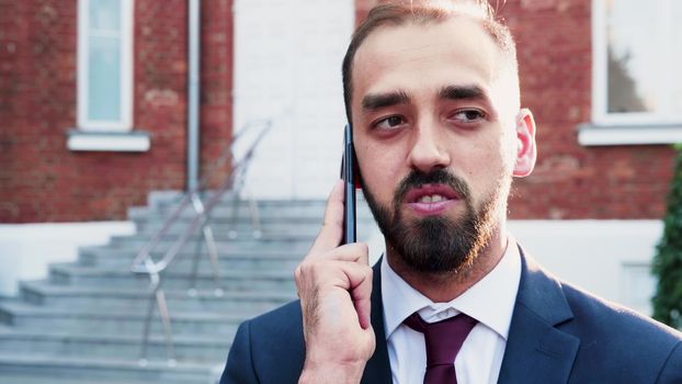 Spinning slow motion of businessman talking on the phone outdoor in the city. Beautiful lens flares from behind