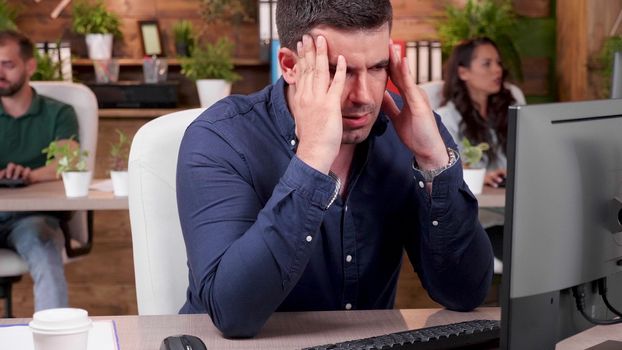 Portrait of stressed and overworked employee trying to work in a busy office